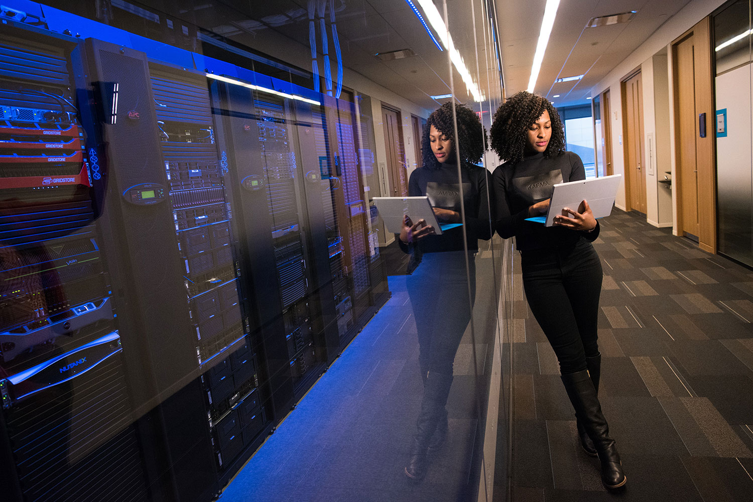 Photo of woman on laptop near server room